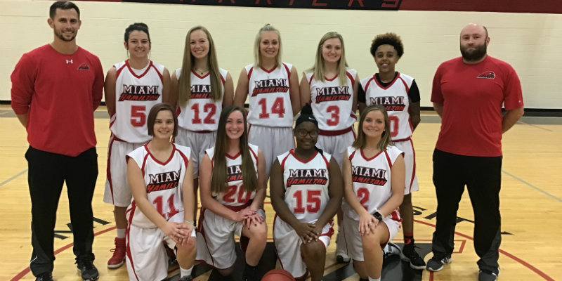 2018-19 Women's basketball team standing in 2 rows on the basketball court